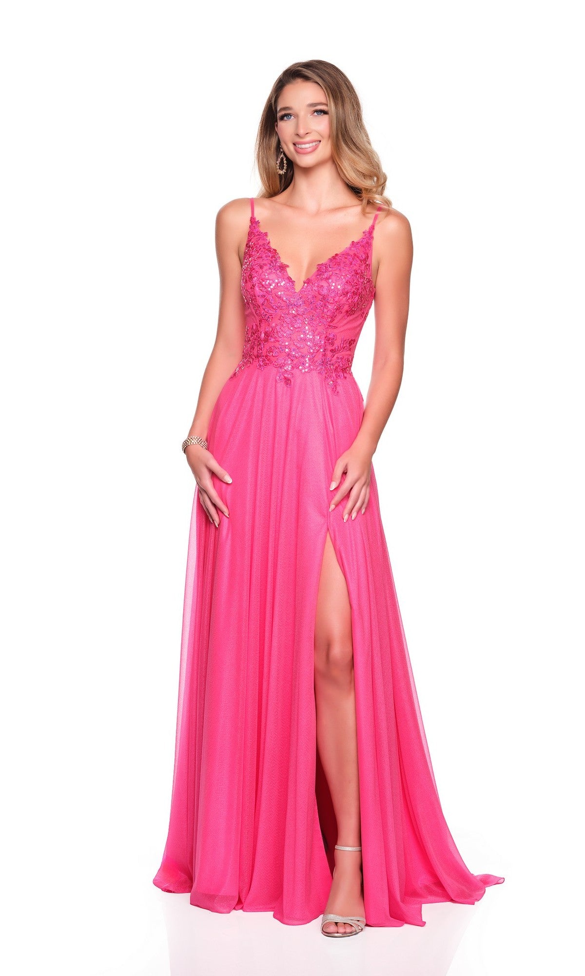 A woman in the Flowy Hot Pink Prom Dress: Dave and Johnny 12570 with an embroidered bodice, thin straps, and a high leg slit smiles in silver heels against a white background.